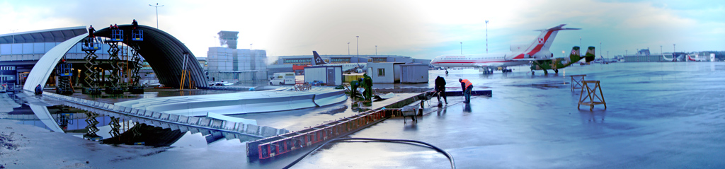 Prefabrykowany lekki hangar łukowy systemu TG Hangars - montaż na płaszczyźnie postojowej lotniska.